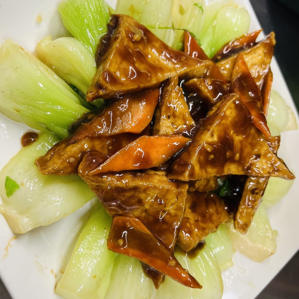 Vietnamese dish with glazed tofu, carrots, and bok choy on a white plate.