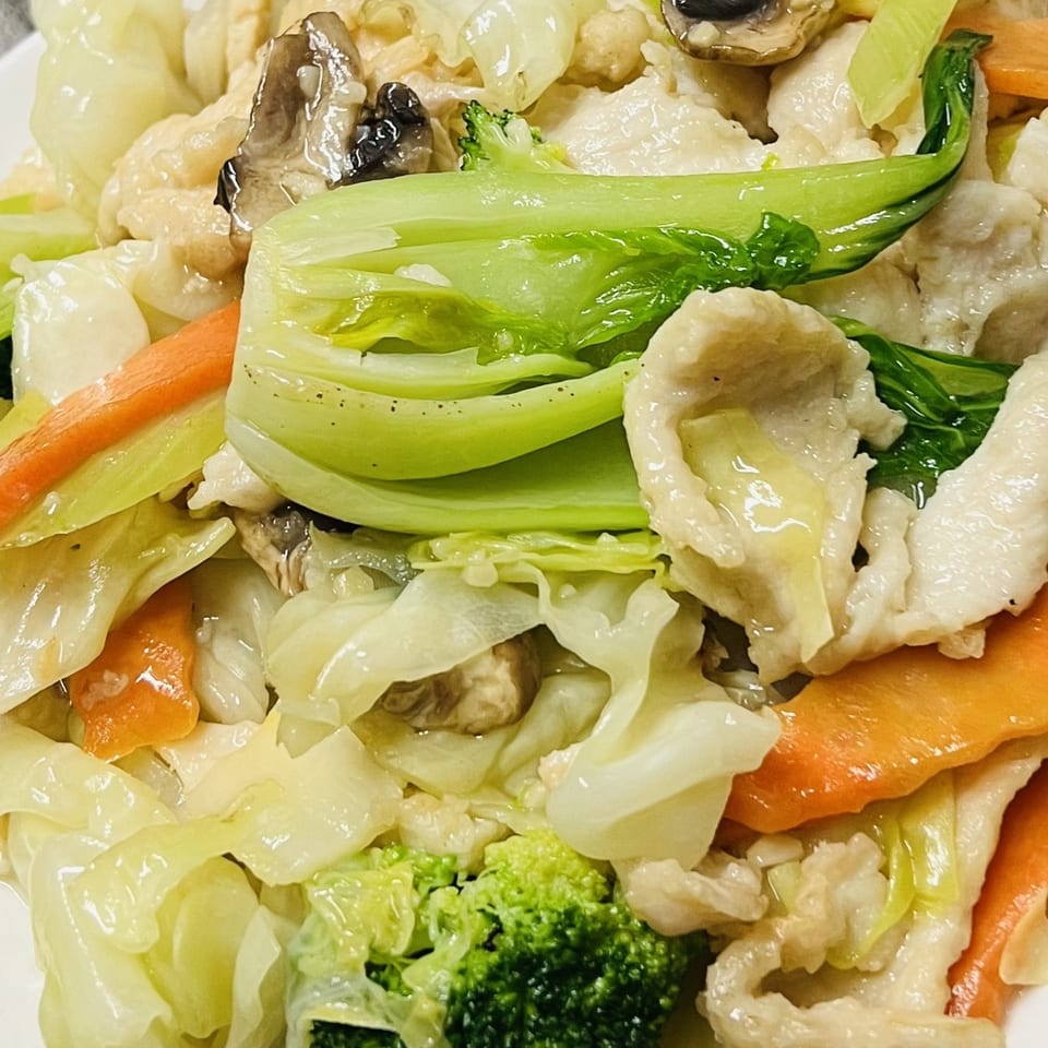 Close-up of a Vietnamese stir-fry with chicken, bok choy, carrots, broccoli, and mushrooms.