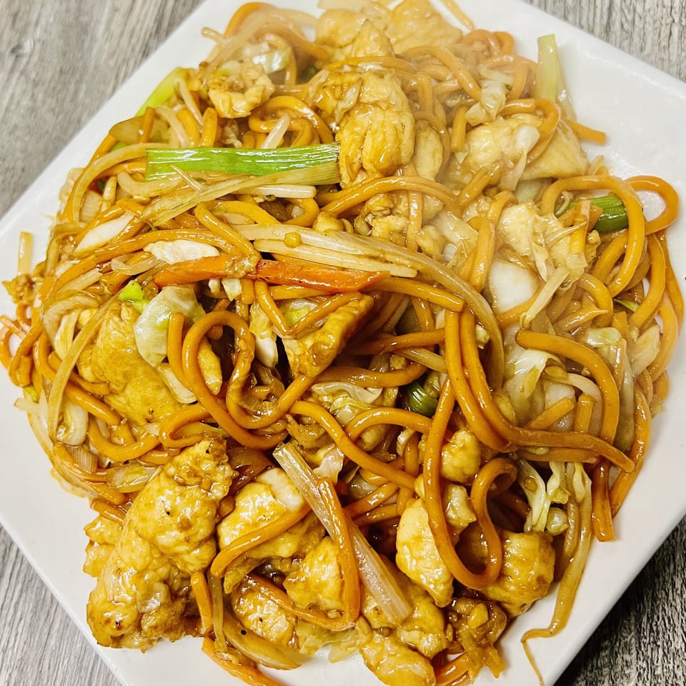 Golden Pho's chicken chow mein with thick noodles, chicken, and vegetables on a white plate.
