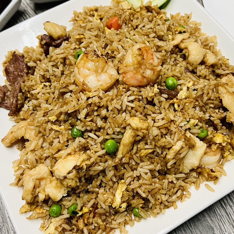 Golden Pho's fried rice with shrimp, beef, chicken, peas, and carrots on a white plate.